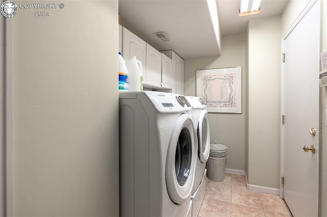 laundry area with light tile patterned floors, washer and clothes dryer, and cabinets