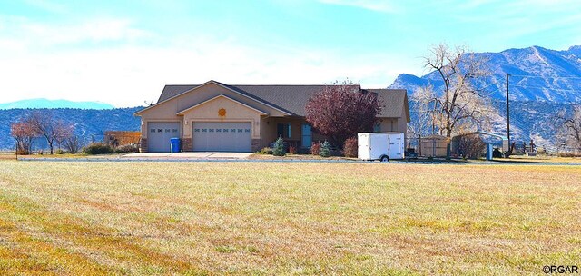 view of front of property featuring a garage, a mountain view, and a front yard