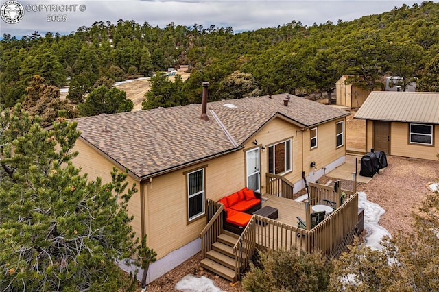 back of property with a deck and roof with shingles