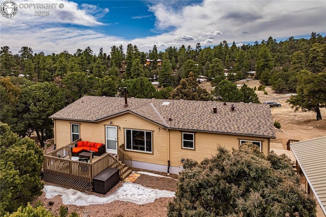 rear view of house featuring a wooden deck, outdoor lounge area, and a shingled roof