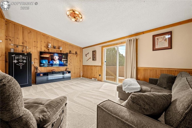 living room featuring a wainscoted wall, a textured ceiling, wooden walls, carpet, and lofted ceiling