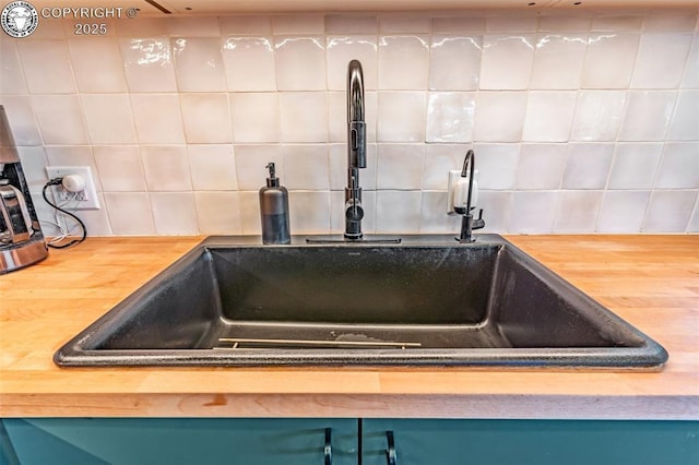 room details with a sink, wooden counters, backsplash, and blue cabinetry