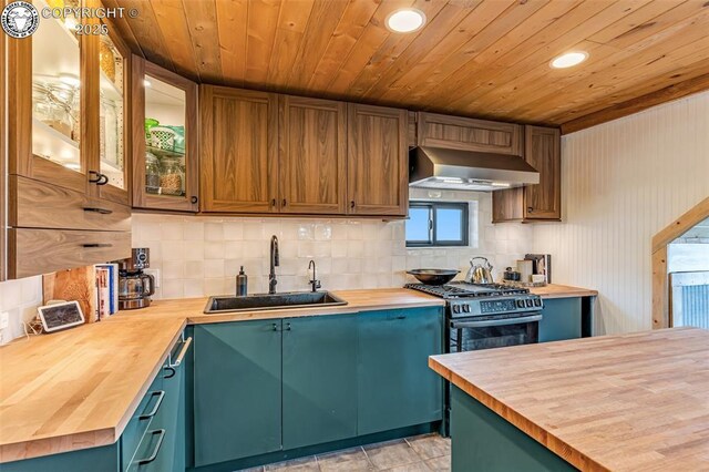 kitchen featuring gas stove, a sink, butcher block countertops, wall chimney range hood, and tasteful backsplash