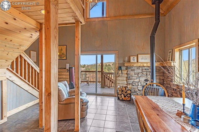 tiled living area with wooden ceiling, wood walls, and high vaulted ceiling