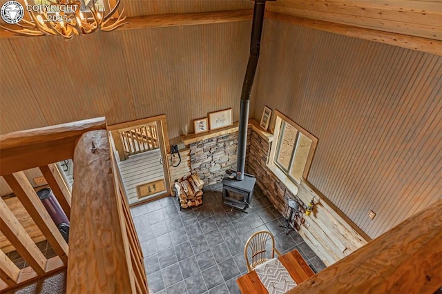 staircase with tile patterned flooring, wooden walls, vaulted ceiling with beams, a wood stove, and an inviting chandelier