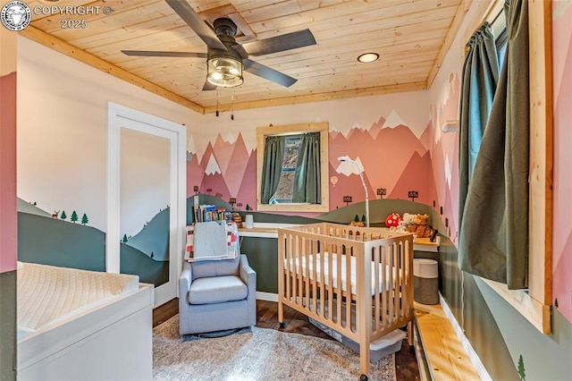 bedroom featuring a nursery area, wood ceiling, wood finished floors, and a ceiling fan