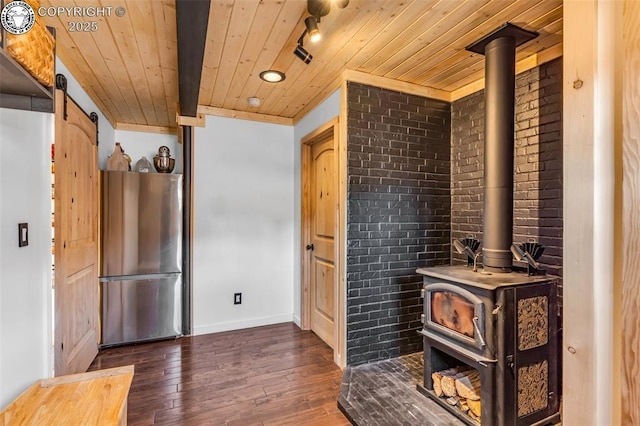 kitchen with wooden ceiling, a wood stove, dark wood-type flooring, and freestanding refrigerator