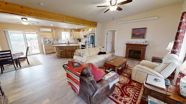 living room featuring beamed ceiling, ceiling fan, and light hardwood / wood-style floors