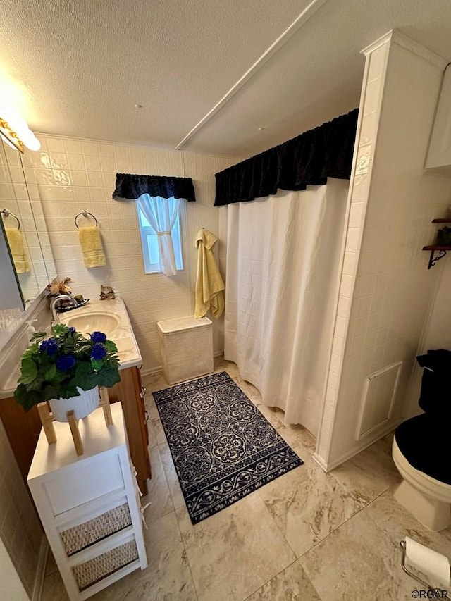 bathroom with vanity, toilet, a textured ceiling, and walk in shower