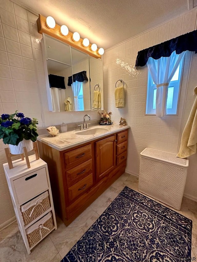 bathroom featuring tile walls, vanity, tile patterned flooring, and a textured ceiling