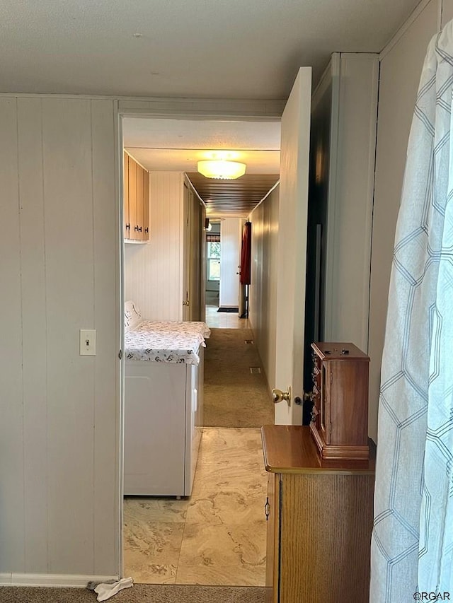 hall with washer / clothes dryer and wood walls