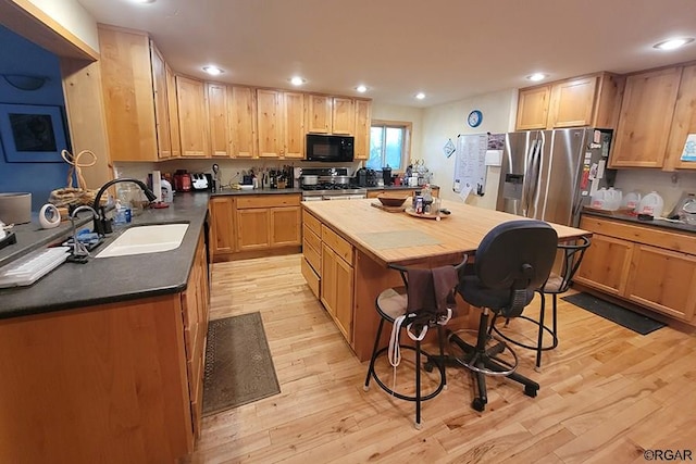 kitchen featuring sink, a breakfast bar area, a kitchen island, stainless steel appliances, and light hardwood / wood-style floors