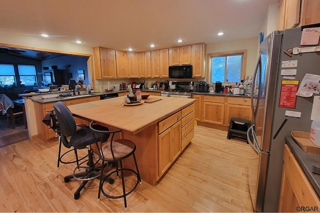 kitchen featuring wooden counters, a kitchen breakfast bar, stainless steel appliances, a kitchen island, and light wood-type flooring