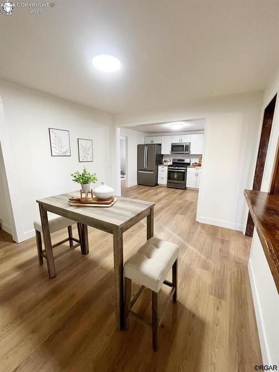 dining area featuring light wood-type flooring and baseboards