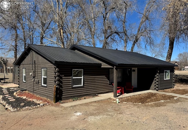 view of front facade featuring metal roof, log siding, and driveway