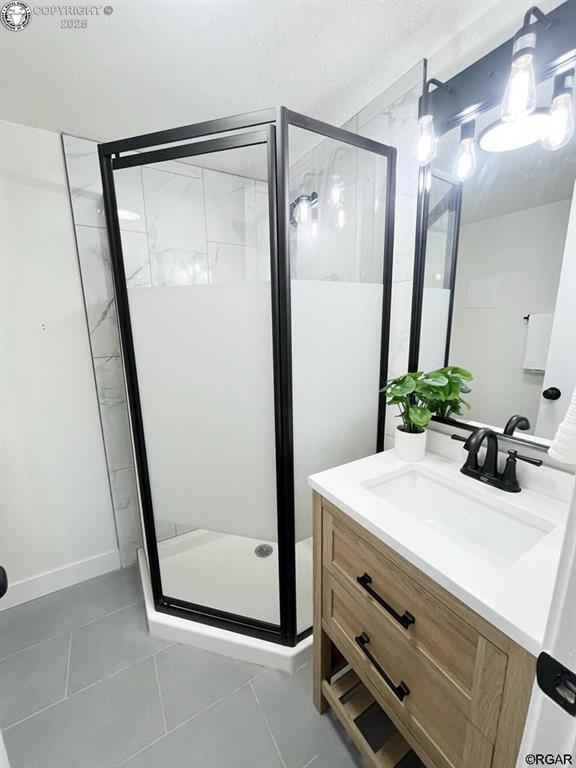 bathroom featuring tile patterned floors, a shower stall, and vanity