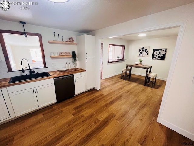 kitchen with wood finished floors, a sink, white cabinetry, wooden counters, and dishwasher