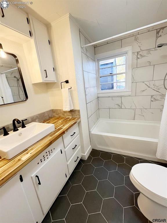 bathroom featuring toilet, tile patterned floors, shower / bath combo with shower curtain, and vanity