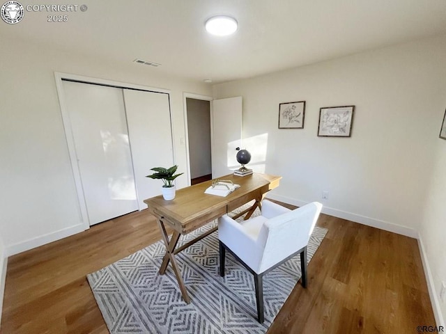 home office featuring wood finished floors, visible vents, and baseboards