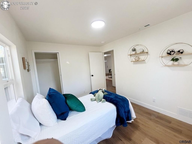 bedroom featuring baseboards, a closet, visible vents, and wood finished floors