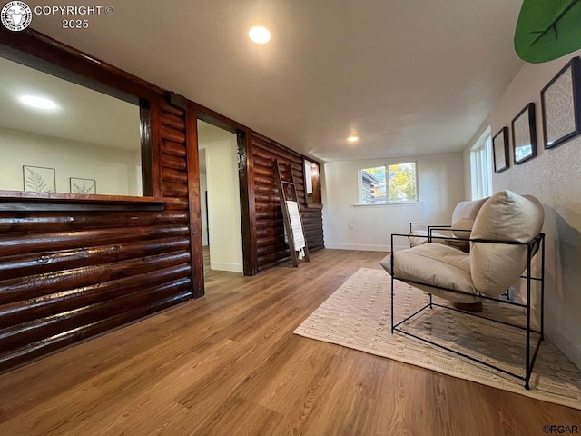 sitting room with recessed lighting, log walls, baseboards, and wood finished floors