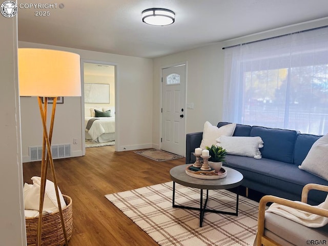 living room featuring baseboards, visible vents, and wood finished floors