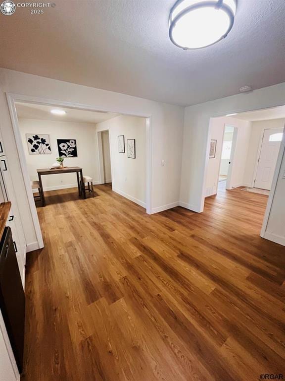 spare room featuring a textured ceiling, baseboards, and wood finished floors