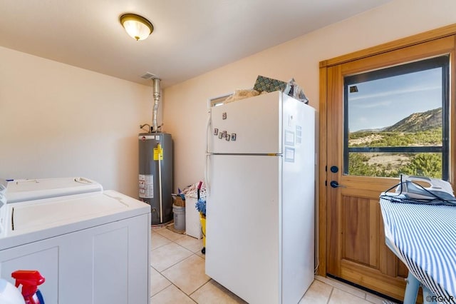 laundry room featuring water heater, a mountain view, washer and dryer, and light tile patterned floors