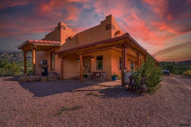 back house at dusk featuring a patio area