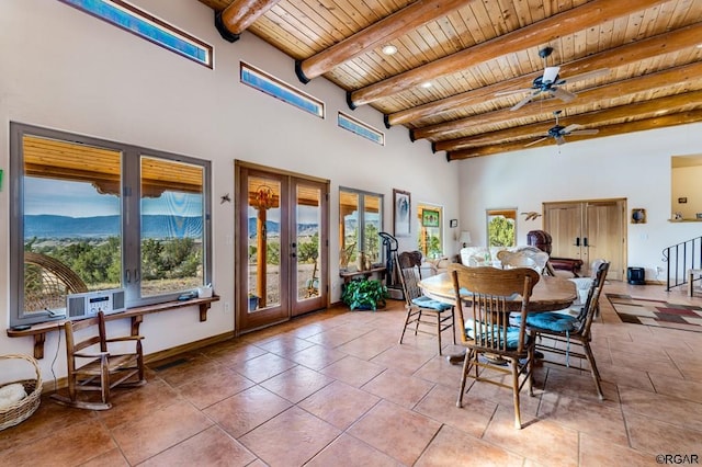 tiled dining room with beam ceiling, a towering ceiling, a mountain view, wooden ceiling, and french doors