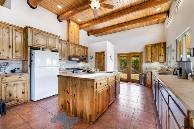 kitchen featuring french doors, wood ceiling, a kitchen island, white fridge, and a towering ceiling