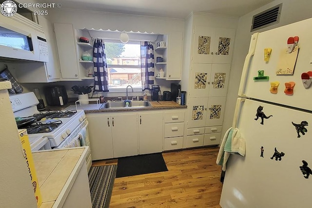 kitchen featuring sink, white cabinets, white appliances, and light wood-type flooring