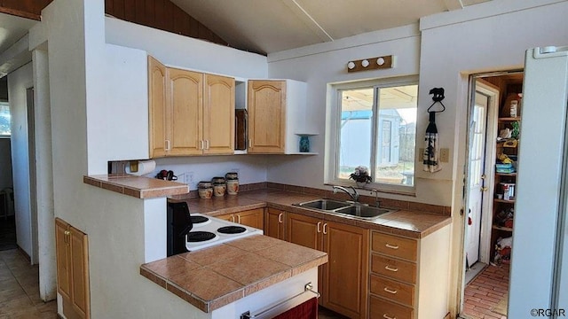 kitchen featuring lofted ceiling, sink, tile countertops, kitchen peninsula, and stove