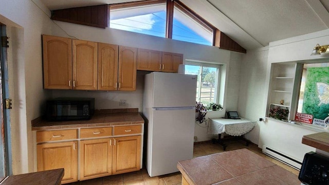 kitchen with tile counters, a baseboard radiator, vaulted ceiling, and white refrigerator