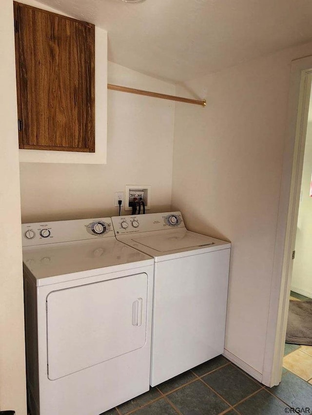 laundry area featuring cabinets, washing machine and clothes dryer, and dark tile patterned flooring