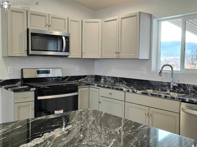 kitchen with stainless steel appliances, sink, dark stone countertops, and gray cabinetry