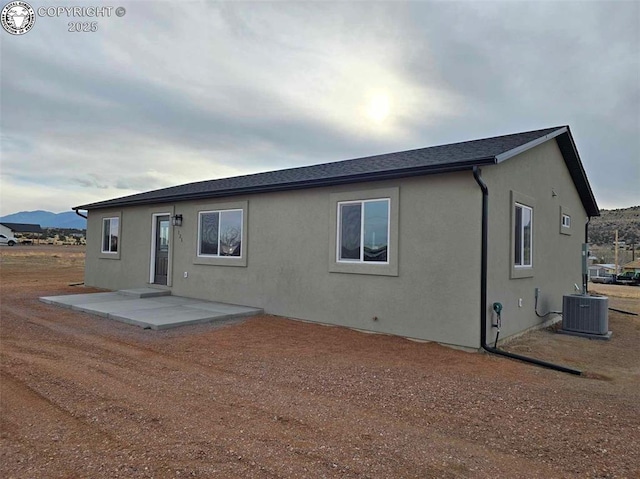 rear view of house with a mountain view, central AC, and a patio area