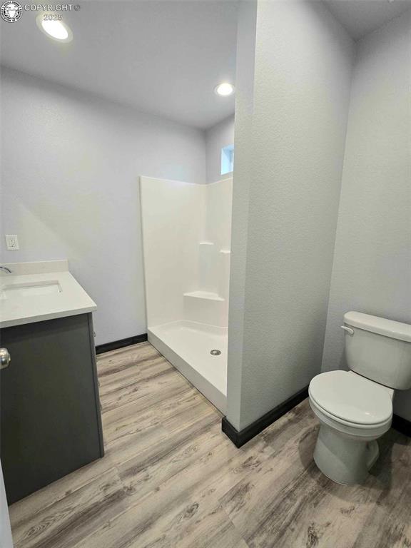 bathroom featuring vanity, hardwood / wood-style flooring, toilet, and walk in shower