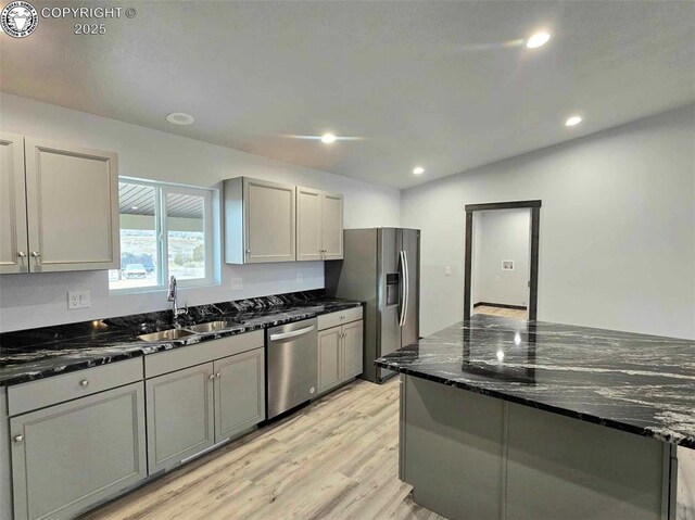 kitchen with gray cabinetry, stainless steel appliances, sink, and dark stone counters