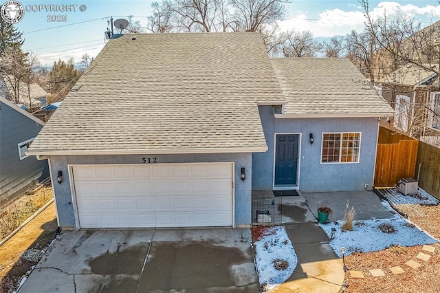 view of front of house featuring concrete driveway, roof with shingles, fence, and stucco siding