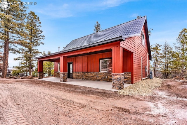 view of front of property with metal roof, stone siding, and board and batten siding