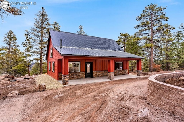 rear view of house featuring metal roof, stone siding, and board and batten siding