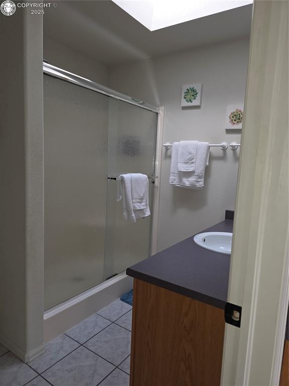 2823 River Run Ct, Canon City, CO 81212 - bathroom with tile patterned floors, vanity, a skylight, and a stall shower