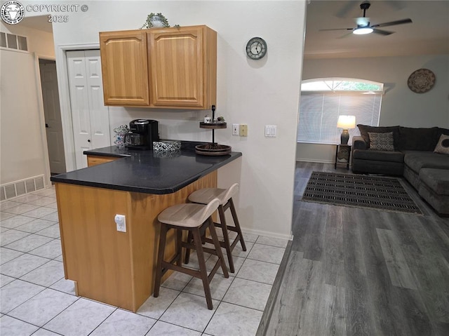 2823 River Run Ct, Canon City, CO 81212 - kitchen featuring a kitchen breakfast bar, dark countertops, light tile patterned floors, and a ceiling fan