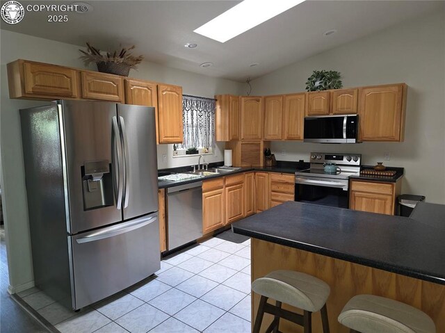 2823 River Run Ct, Canon City, CO 81212 - kitchen with appliances with stainless steel finishes, light tile patterned floors, a breakfast bar area, dark countertops, and vaulted ceiling