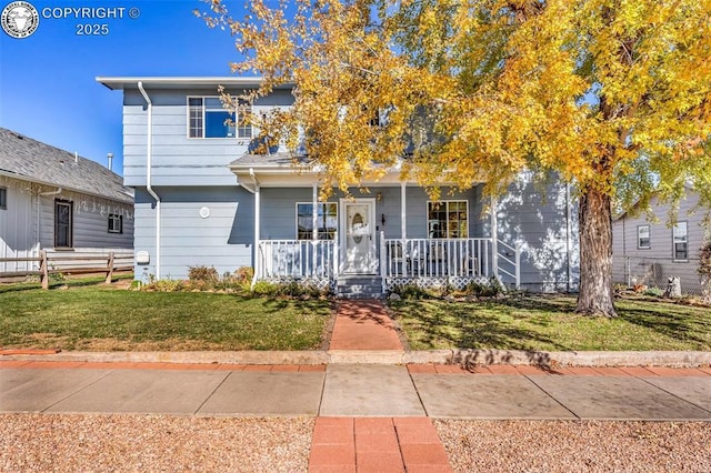 view of front facade with a porch, a front yard, and fence