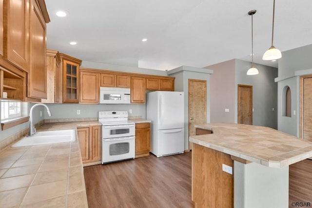 kitchen featuring sink, a center island, pendant lighting, white appliances, and light hardwood / wood-style floors