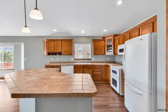 kitchen featuring tile countertops, decorative light fixtures, sink, light hardwood / wood-style floors, and white appliances