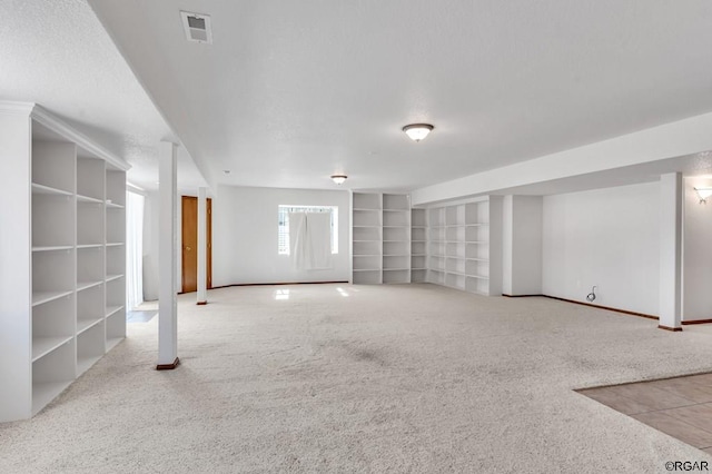 basement featuring built in shelves and light colored carpet