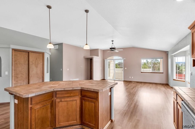 kitchen with dishwasher, tile counters, a center island, and hanging light fixtures